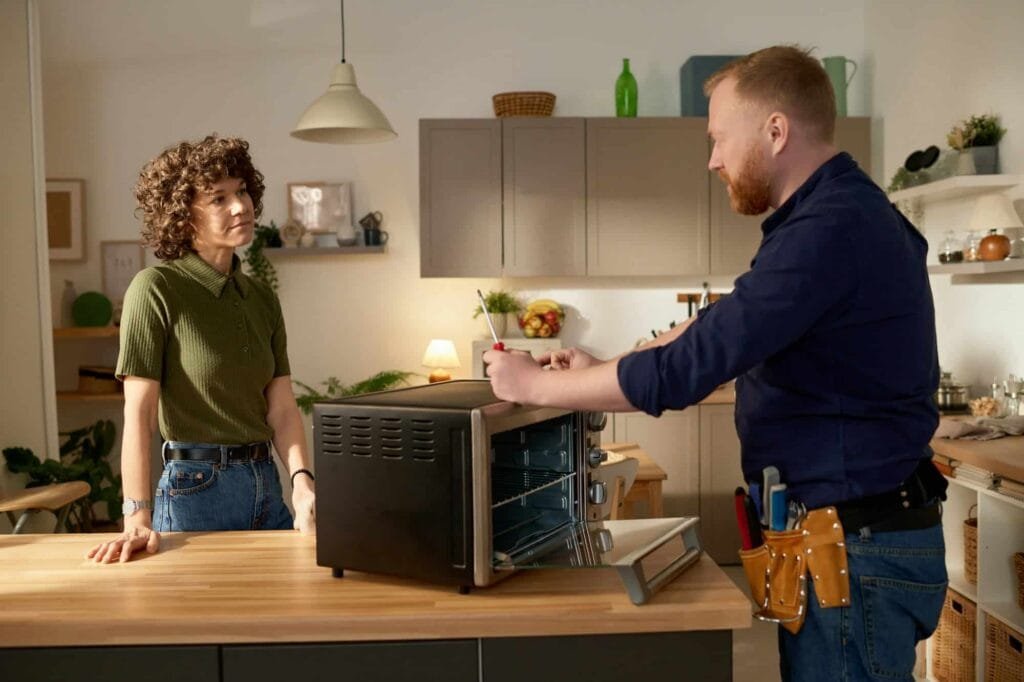 Appliance repair technician fixing broken microwave at home – Expert microwave repair service.