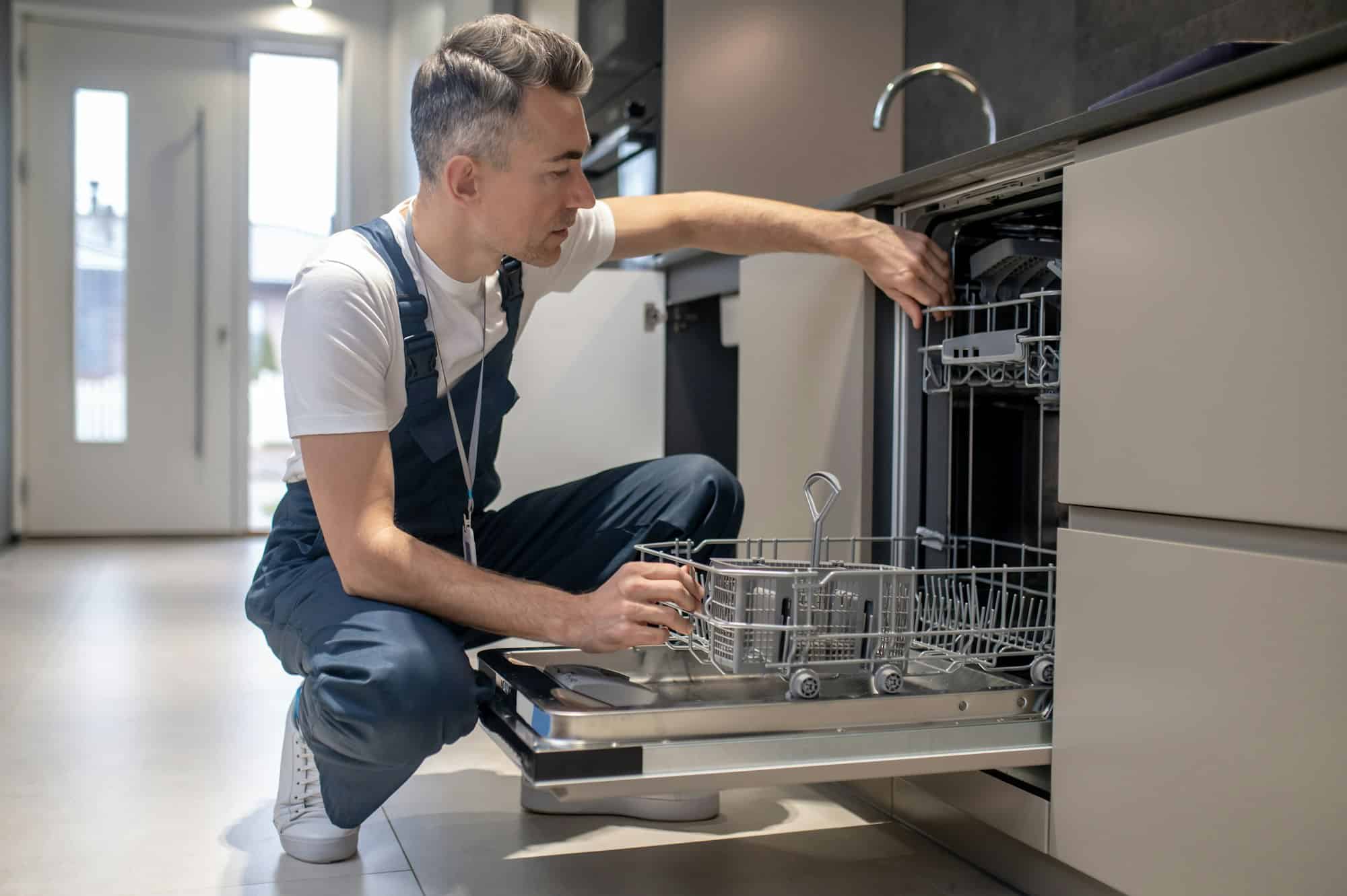 Man carefully examining an open dishwasher during residential kitchen appliance repair in New Jersey.