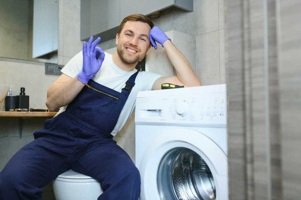Man repairing a washing machine as part of residential laundry appliance repair services in Chicago.